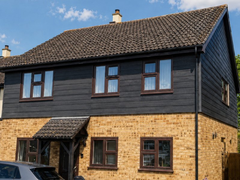A detached house in Kent with black cladding to the first floor above yellow brickwork
