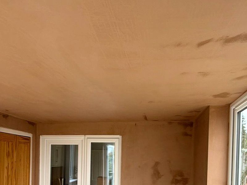 A freshly skimmed ceiling and wall junction, plaster still drying