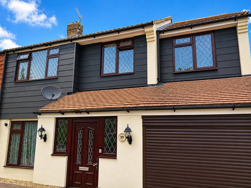 Dark cladding to the first floor of a house with a cream rendered elevation below