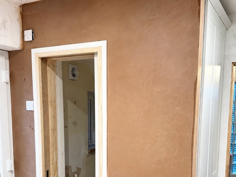 A freshly skimmed hallway with a plastered door opening and new plaster still drying