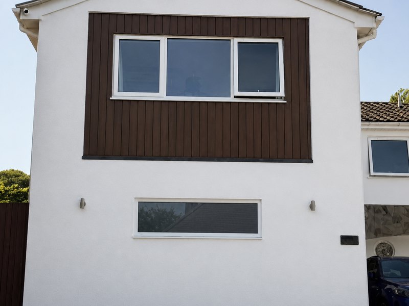 A white rendered gable with a dark timber-effect cladding panel around the window