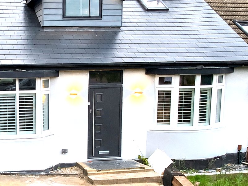 A chalet-style property finished in white render with grey cladding to the dormers