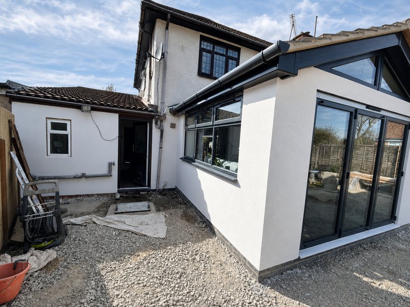 A white rendered extension with a lantern roof and dark grey bi-fold doors