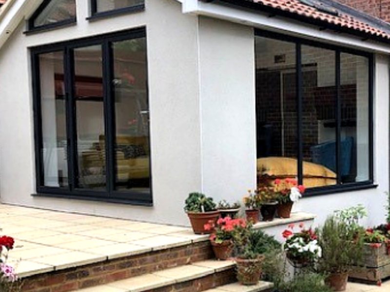 A white rendered extension with dark grey bi-fold doors