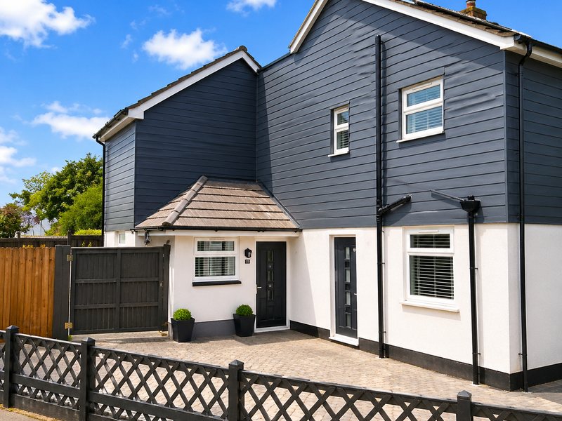 A house with white render to the ground floor and navy cladding above