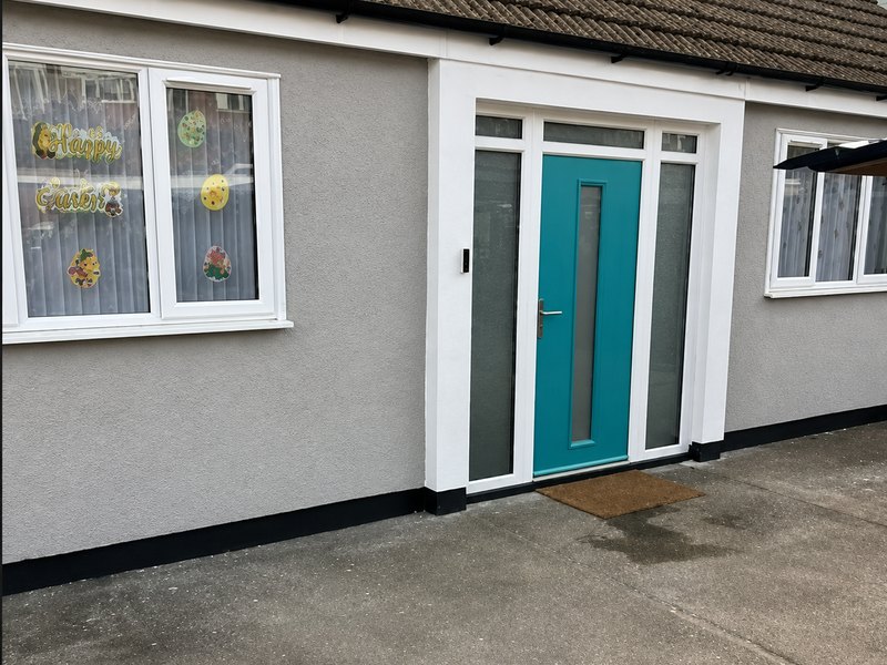 A bungalow frontage finished in grey silicone render with a teal front door