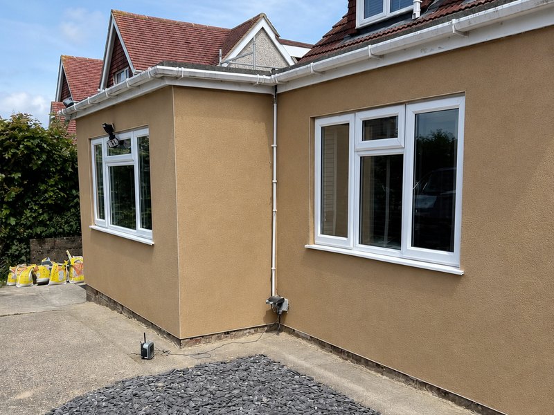 A chalet bungalow finished in a warm buff silicone render with white windows